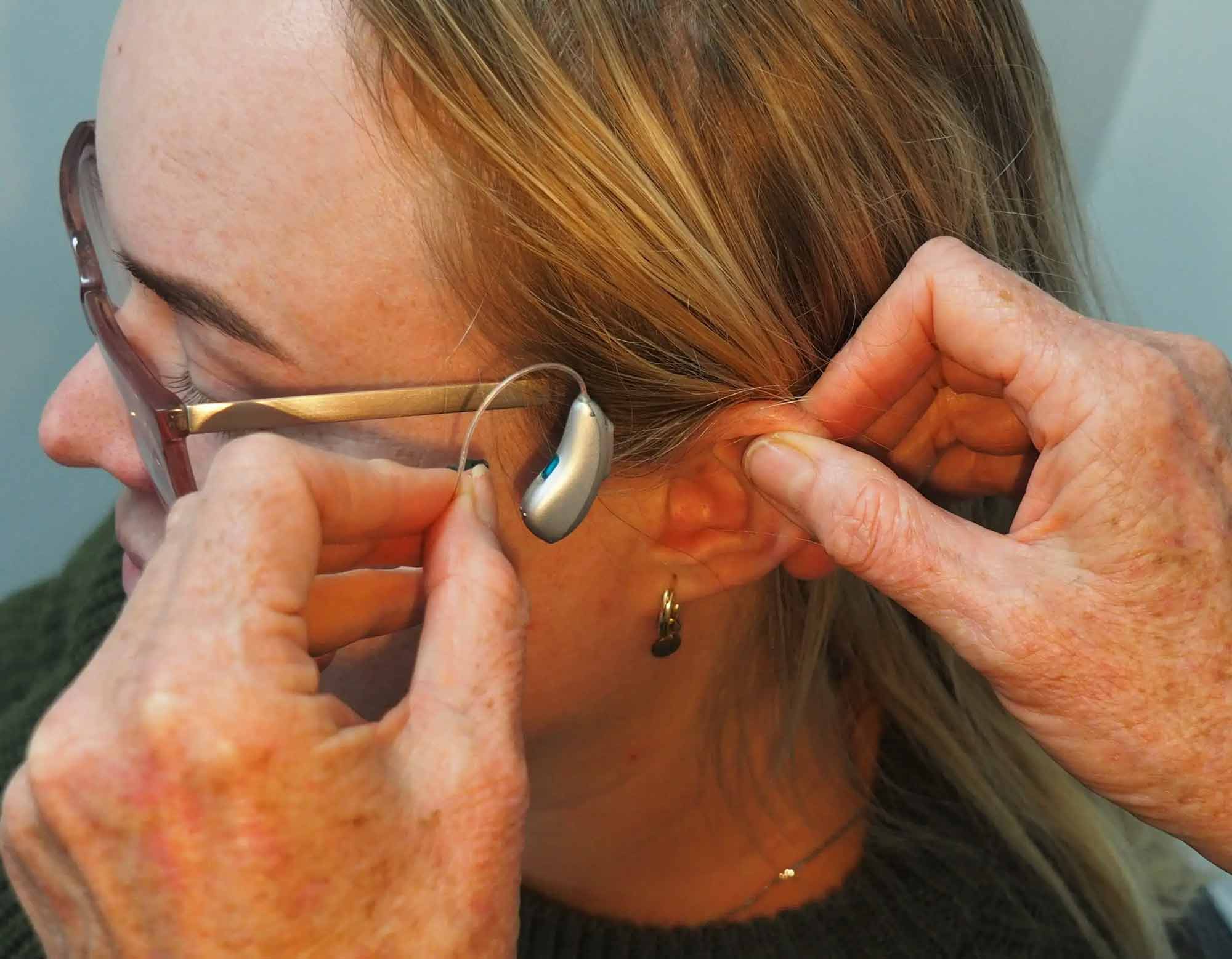 Kvinna tar på sig en hörapparat