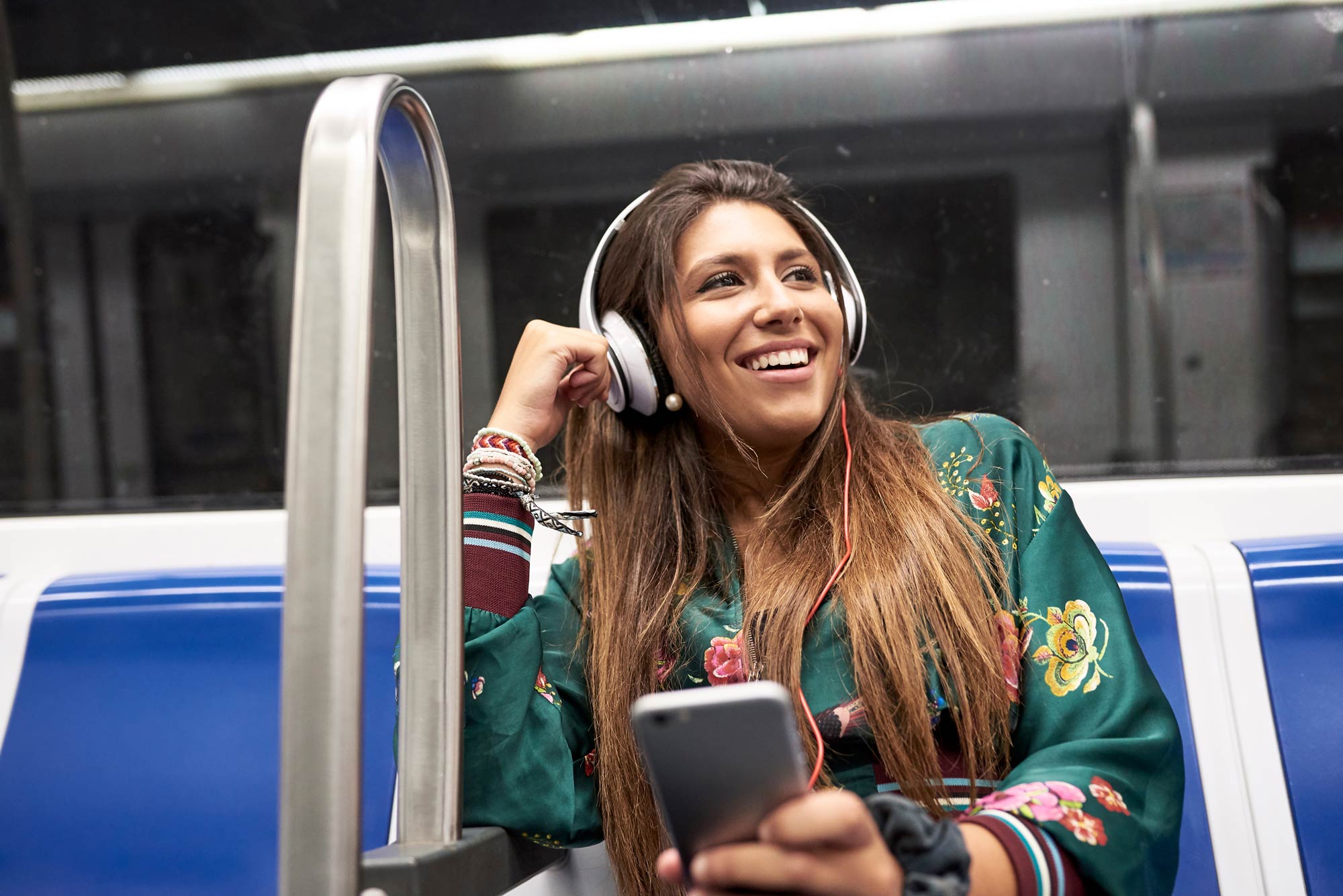 En kvinna med hörlurar sitter på tunnelbanan