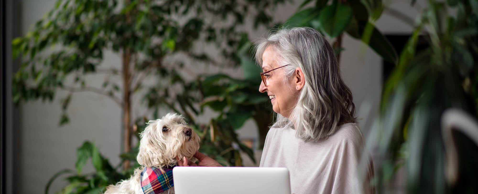 En kvinna sitter vid en dator med sin hund