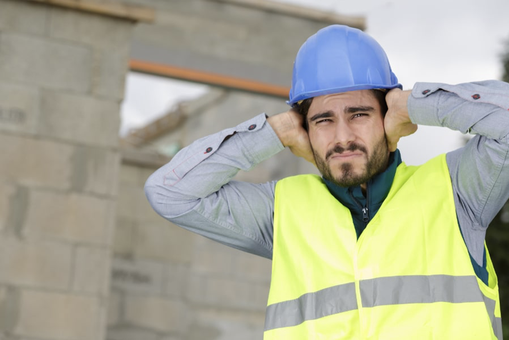 En byggarbetare håller för öronen