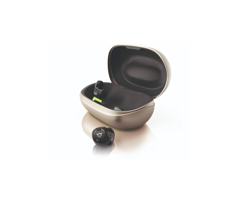 Öppen laddningsetui i beige med svart insida för hörapparater; en svart hörapparat sitter i etuiet och en ligger framför på en ljus bakgrund.